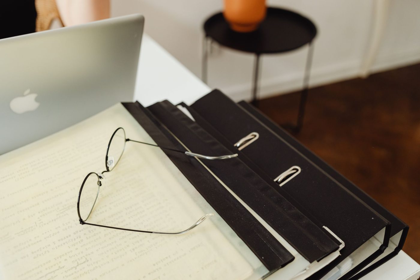Laptop, Brille und Aktenordner auf dem Schreibtisch bei der Lohnabrechnung